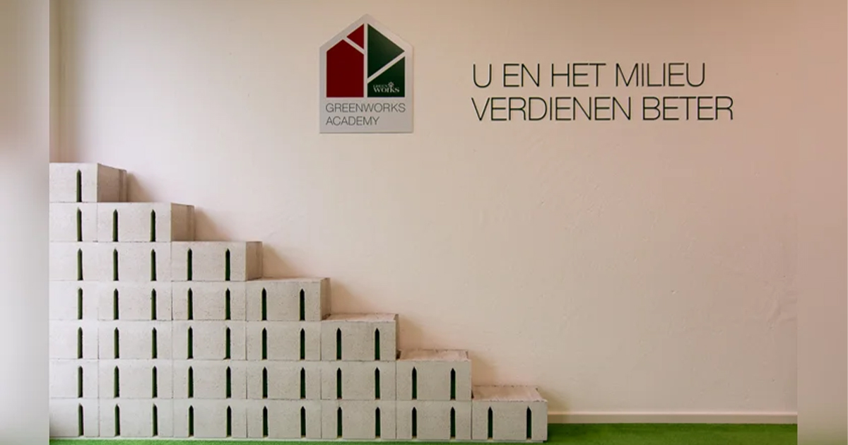 Un escalier en blocs blancs avec des accents verts est placé contre un mur blanc portant le logo « Greenworks Academy » et le texte « U en het milieu verdienen beter » en néerlandais.